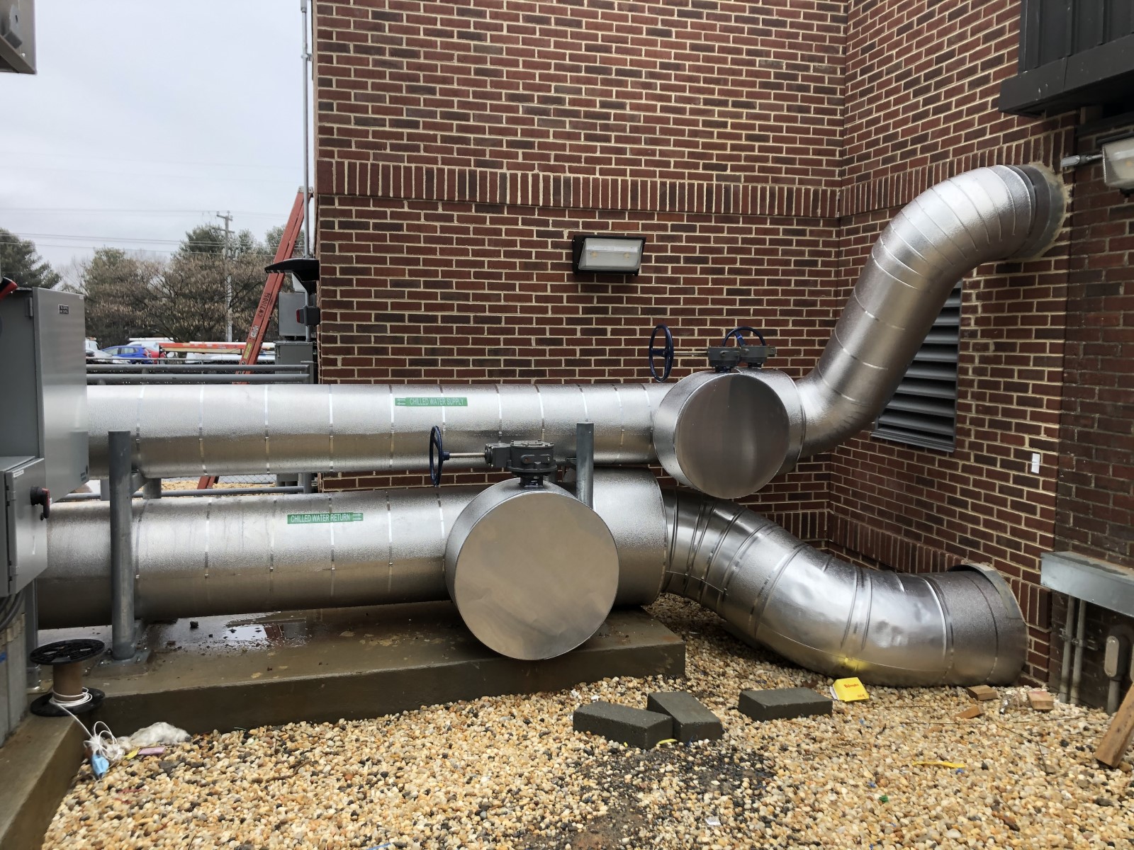 Industrial pipes leading away from a building and into HVAC machinery.
