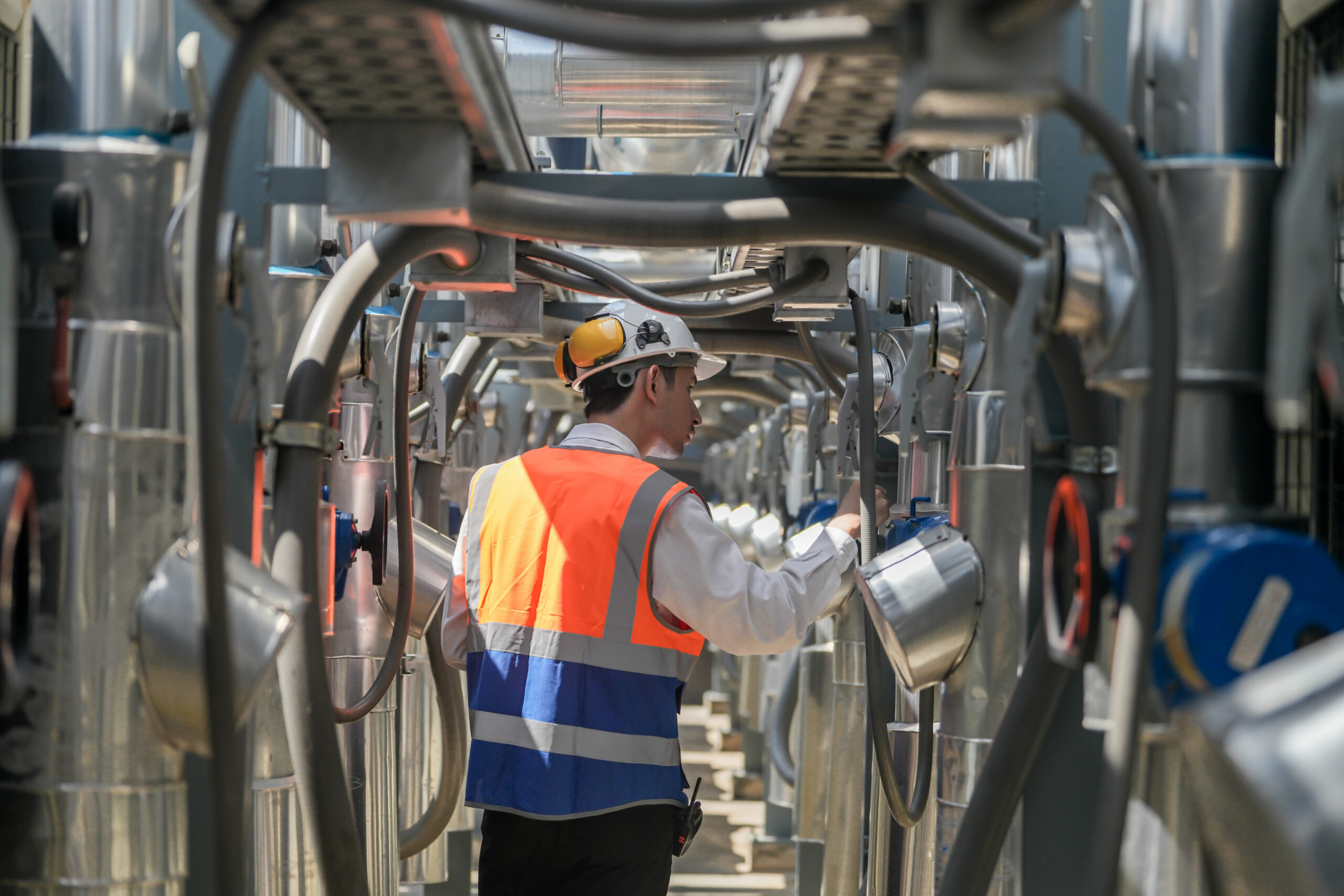 An engineer inspects the heat tracing system on industrial pipes.